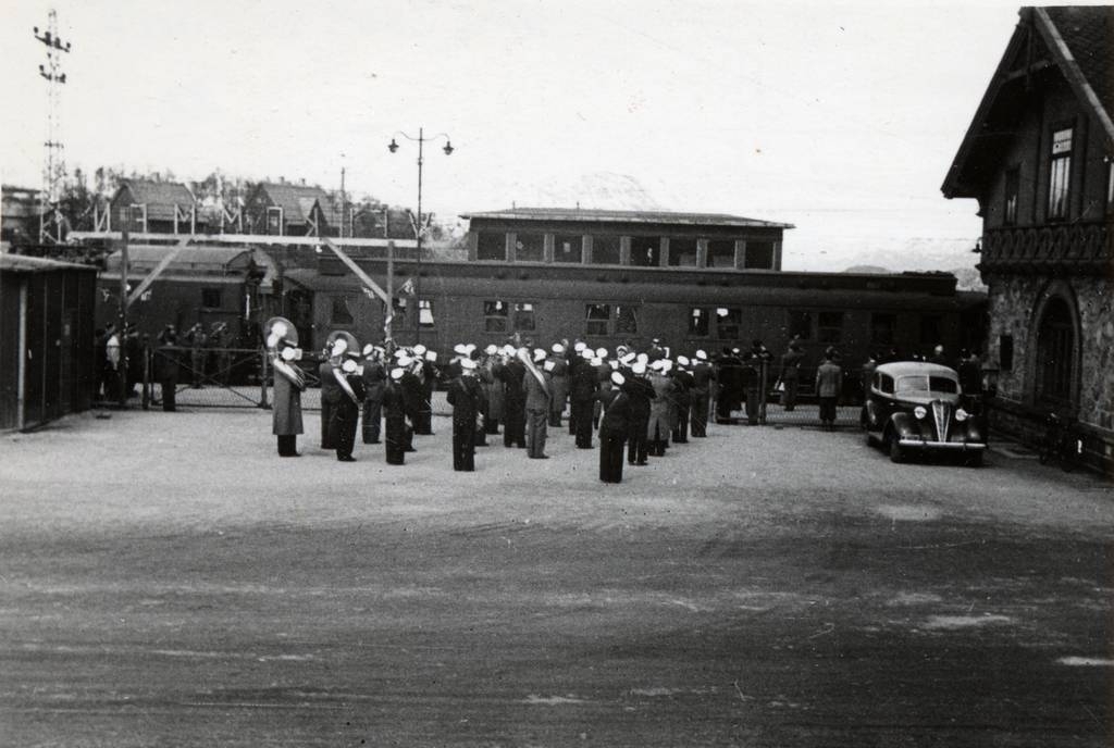 Musikk korps foran stasjonsbygningen på Jernbanestasjonen i Narvik. Soldater fra Sverige ankommer.