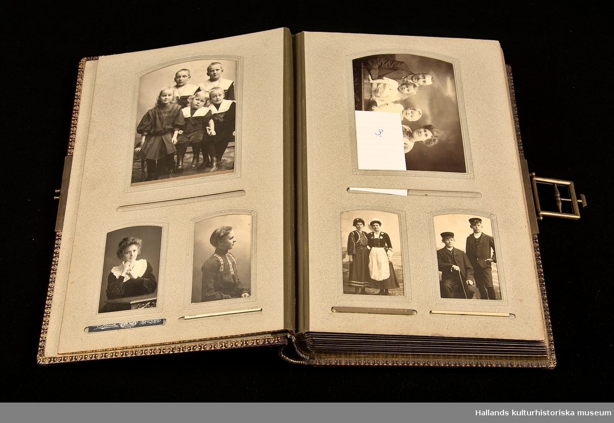 Vinrött fotoalbum (a) i svart låda (b) innehållande fotografier från tiden 1890-1930. Lås i mässing. Arken guldfärgade på kanterna.