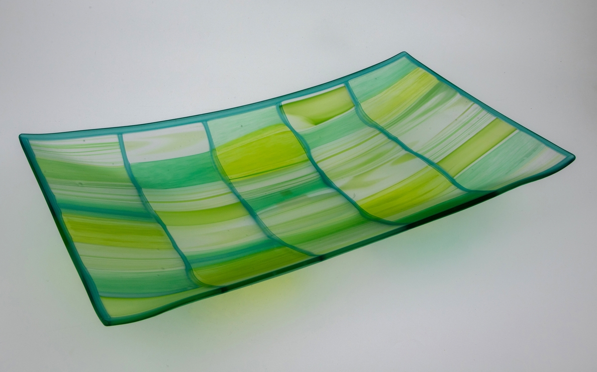Rektangulært fat med konveks form i halvgjennomskinnelig glass, tilvirket ved hjelp av fusing og slumping. Fatets innerside er mattet ved hjelp av etsing. Dekoren består av rektangulære felter i klart glass, hvor det er innslag av grønt i ulike nyanser, omgitt av mørkegrønne konturlinjer.