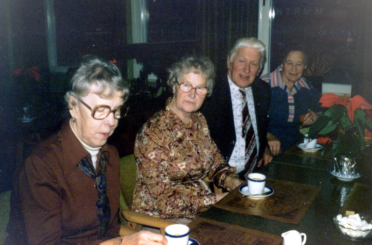 Hobbylokalens pensionärer är på utflykt, okänd plats och årtal. Från vänster: Elin Johansson (1906 - 1980) samt tre okända personer dricker kaffe. På bordet står en röd julblomma.