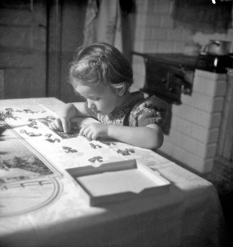 En liten flicka lägger puzzel vid köksbordet i en lägenhet i Jönköping.
