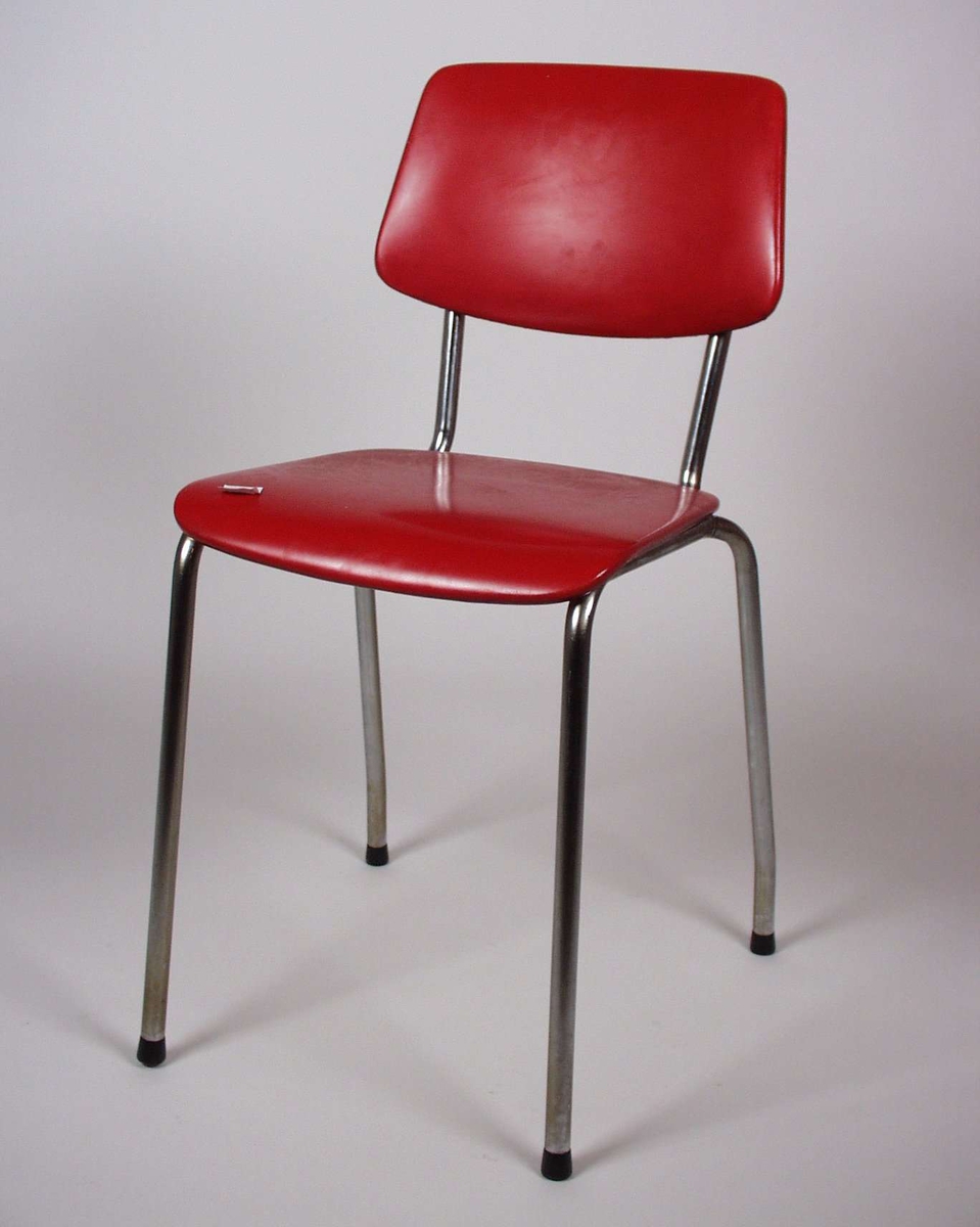Stolen er av metall med formpresset bjørk til sete og rygg, dette er trukket med rødt kunstskinn.