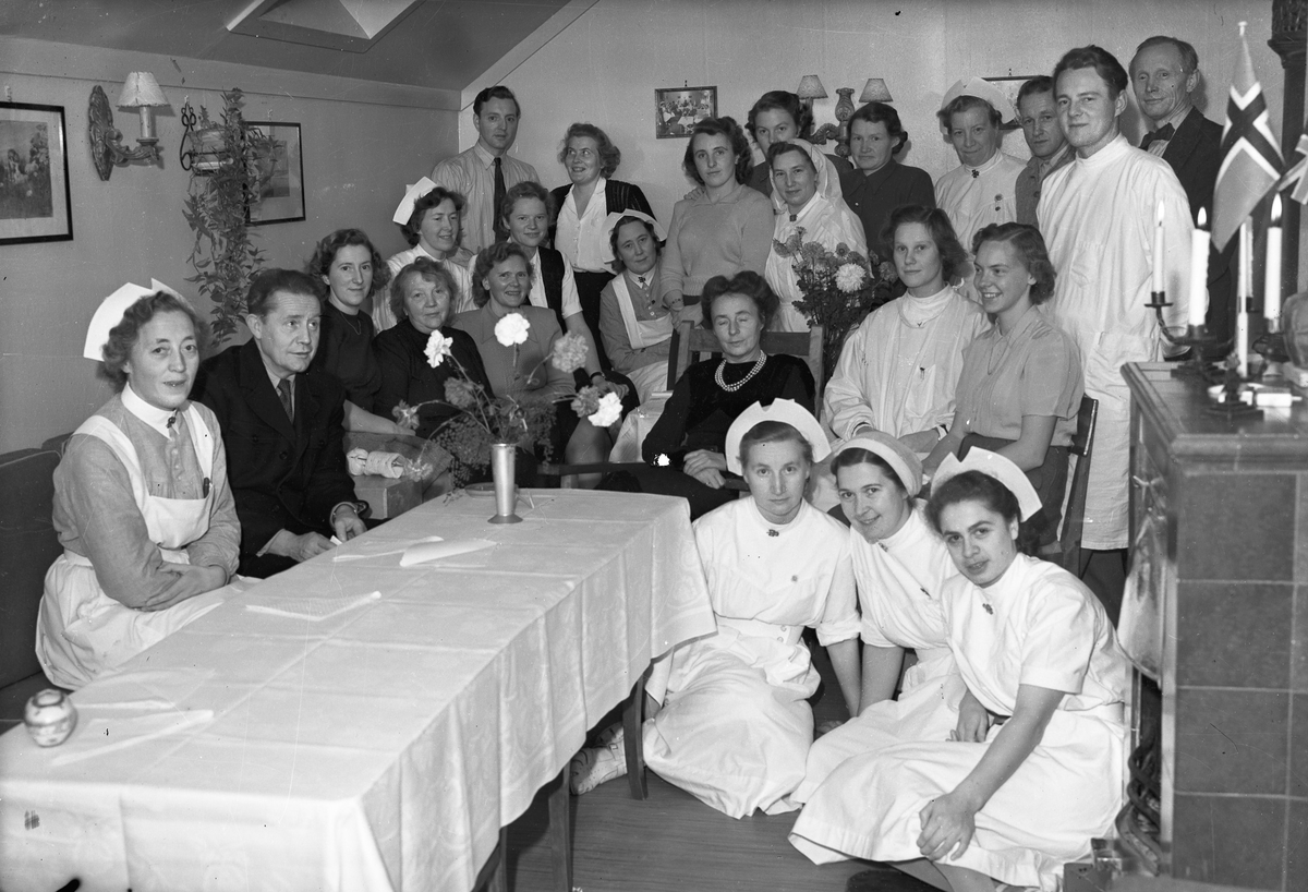 Personale i hvite uniformer. På kvinnenes uniformer har de merket til NKS – Norske Kvinners Sanitetsforening.