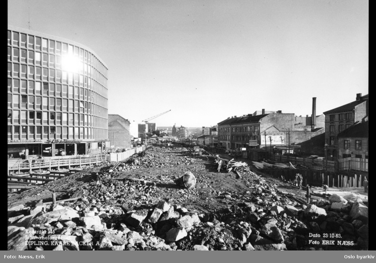 Byggingen av Jernbanetorget stasjon, Traktorhuset i Nygata 12 til venstre, Vaterland saneres. Bilde datert 23. oktober 1963.