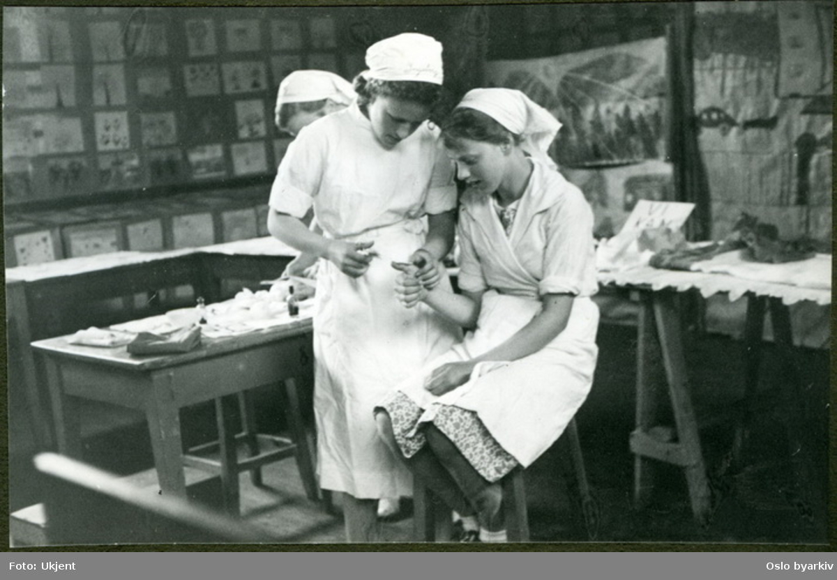 Tre jenter som øver seg på førstehjelp. (Merk spesiell ortografi i bildets originale tittel.) Albumtittel: "Sofienberg skole femti år - første september 1933."