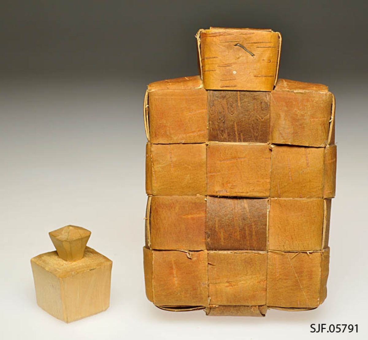 Saltflaska er flettet av never. Ved tuten er det brukt stiftemaskin for å feste nevra. Proppen er av ubehandlet bjørk. Den er laget av Mentz Åsen, Grue Finskog ca. 1963, og kjøpt inn til museet da. 
