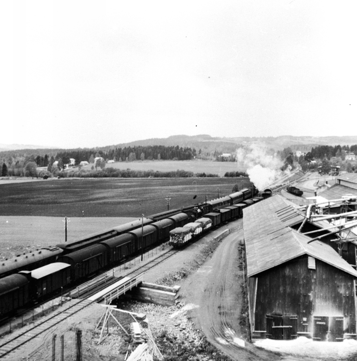 2 tog krysser ved Brumunddal jernbanestasjon, til høyre er fabrikkområdet til Berger Langmoen A/S.