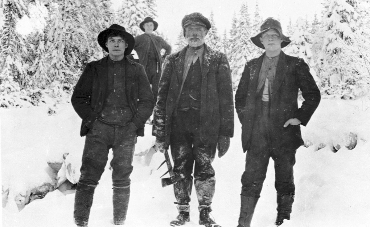 4 tømmerhoggere i Ulvemarka, Brøttum, Ringsaker. Fra venstre er Edvard Dahlsveen, tømmermåler med tømmerklave er Anton Torgersen Vea, ukjent, ukjent.