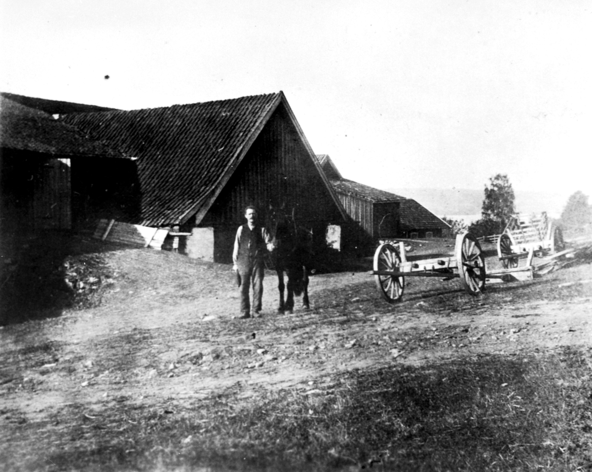 Stallkar Olivius Maurud f.1869 med hest ovenfor gamlelåven på Hovelsrud, Helgøya. Låven brant i 1934.