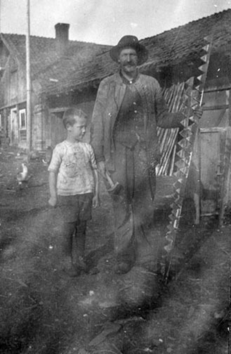 Mann og gutt foran grisehus. Syver Nilsen (1874-1960) og Erling Feiring (1915-1988) på Bjørnstad, Nes, Hedmark.