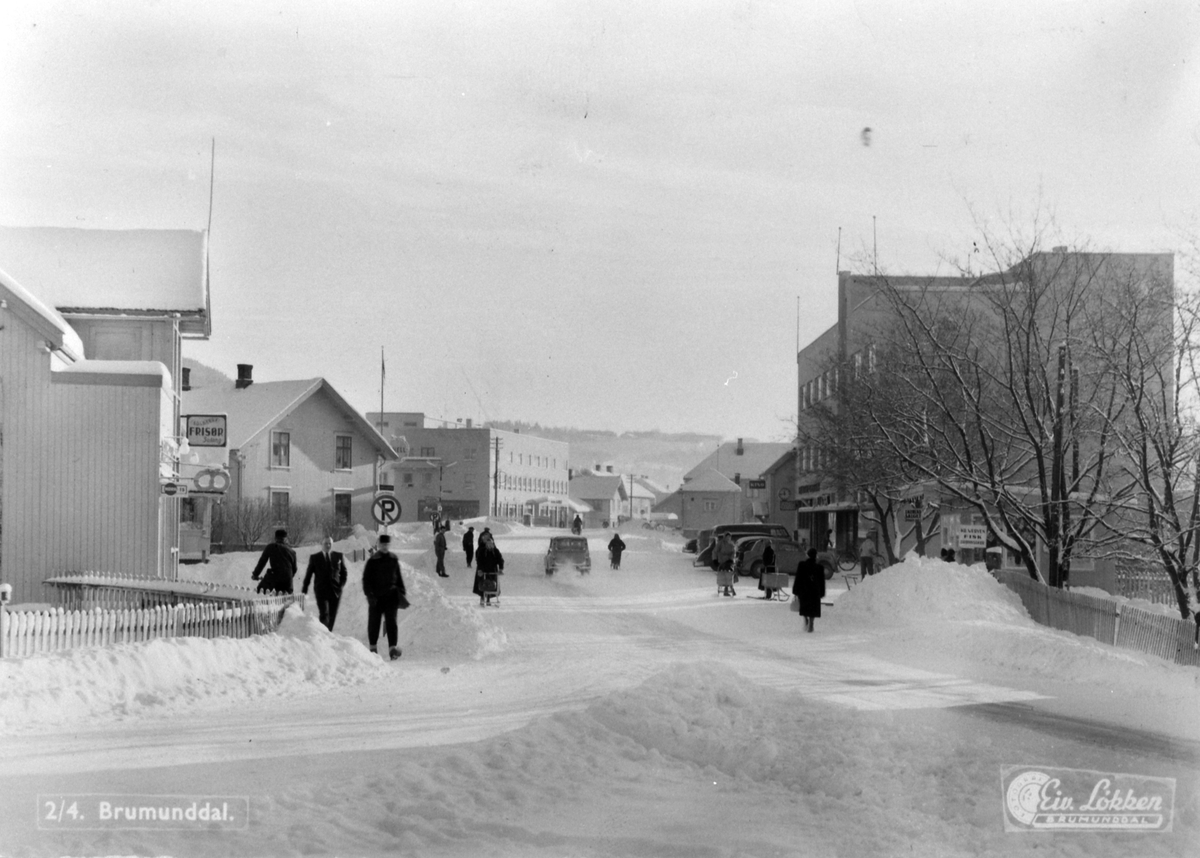 Ringsakervegen, Furnesvegen. Til venstre er Solberg Frisørsalong, bakeri, Aage Thomassen, Gudahlgården, til høyre er Grand Hotell, Brumunddal, 1955-60.