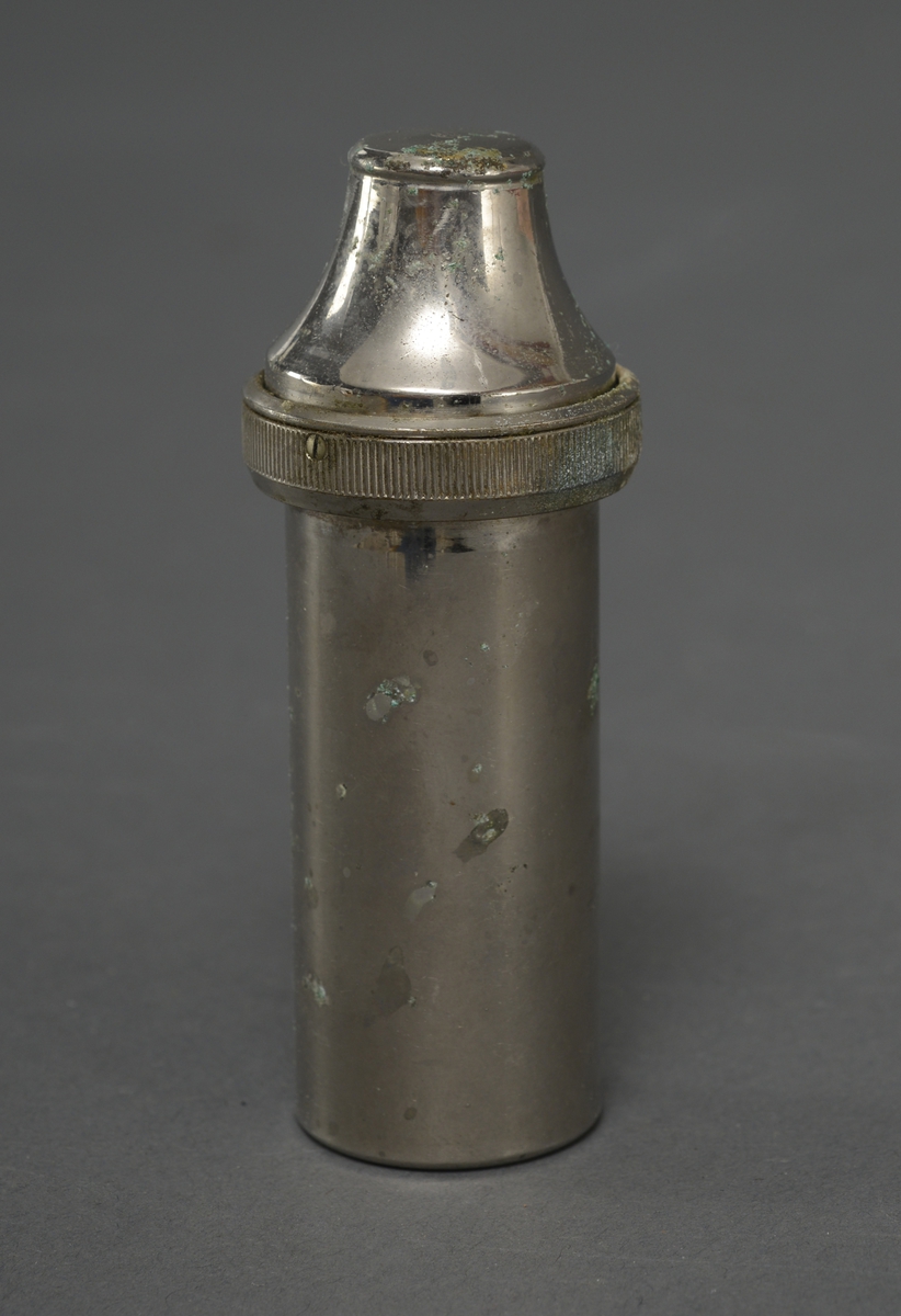 Sylindrisk beholder av metall, med plass til en sprøyte med kanyler. Beholder kan fylles med desinfiserende væske.
