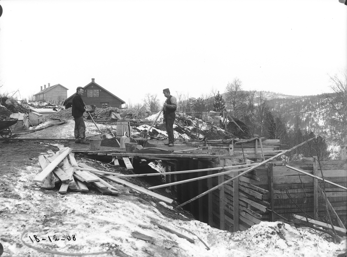 Støping av grunnmurer på formannshus syd for brakke 25. To menn i arbeid.
