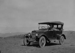 En piperøkende bestyrer H. A. Cannon i sin tjenestebil, en O