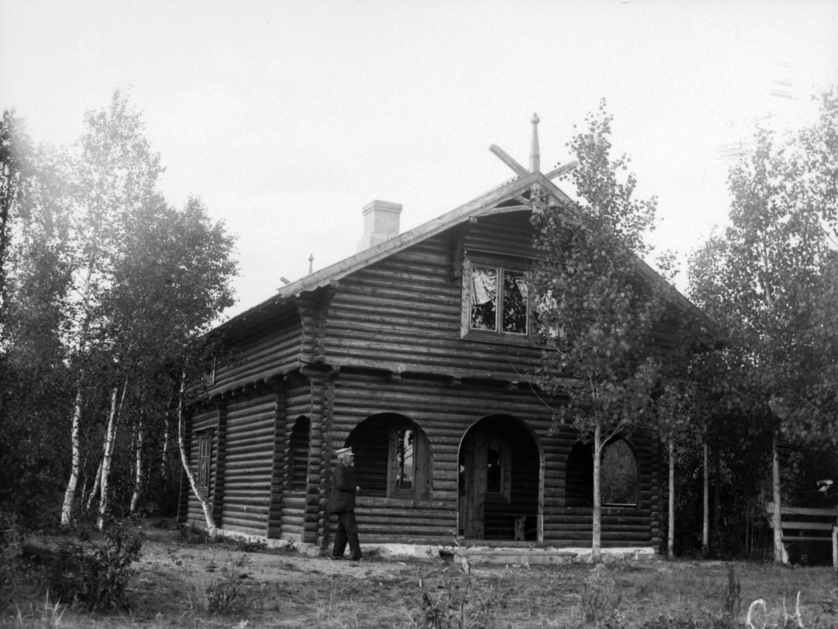 En mann foran et laftet hus. - Anno Domkirkeodden / DigitaltMuseum