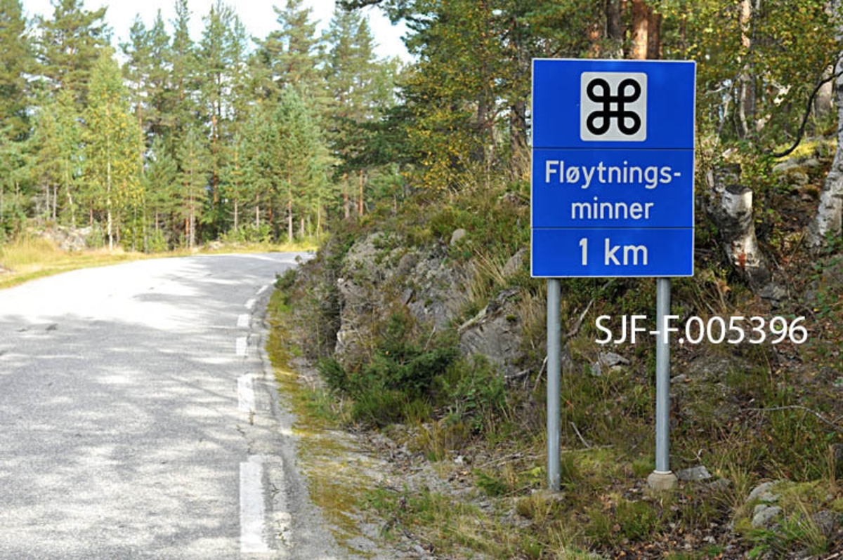 Informasjonsskilt om «fløytningsminner» ved riksveg 364 («Hovinvegen») i Notodden kommune i Telemark.  Det dreier seg om et blått skilt på to galvaniserte jernstolper.  Øverst på skiltet er det et kvitt kvadrat med en valknute – et kringleformet korssymbol – som viser at trafikantene nærmer seg severdigheter.  En kvit tekst under valknuten forteller at det dreier seg om «Fløytningsminner» med avkjøring fra Hovinvegen en kilometer lengre framme (ved Hegnadalen).  Kulturminnene det dreier seg om er Raudammen og Rautunnelen, hvor forholdene er tilrettelagt for publikum i form av en kultursti. 