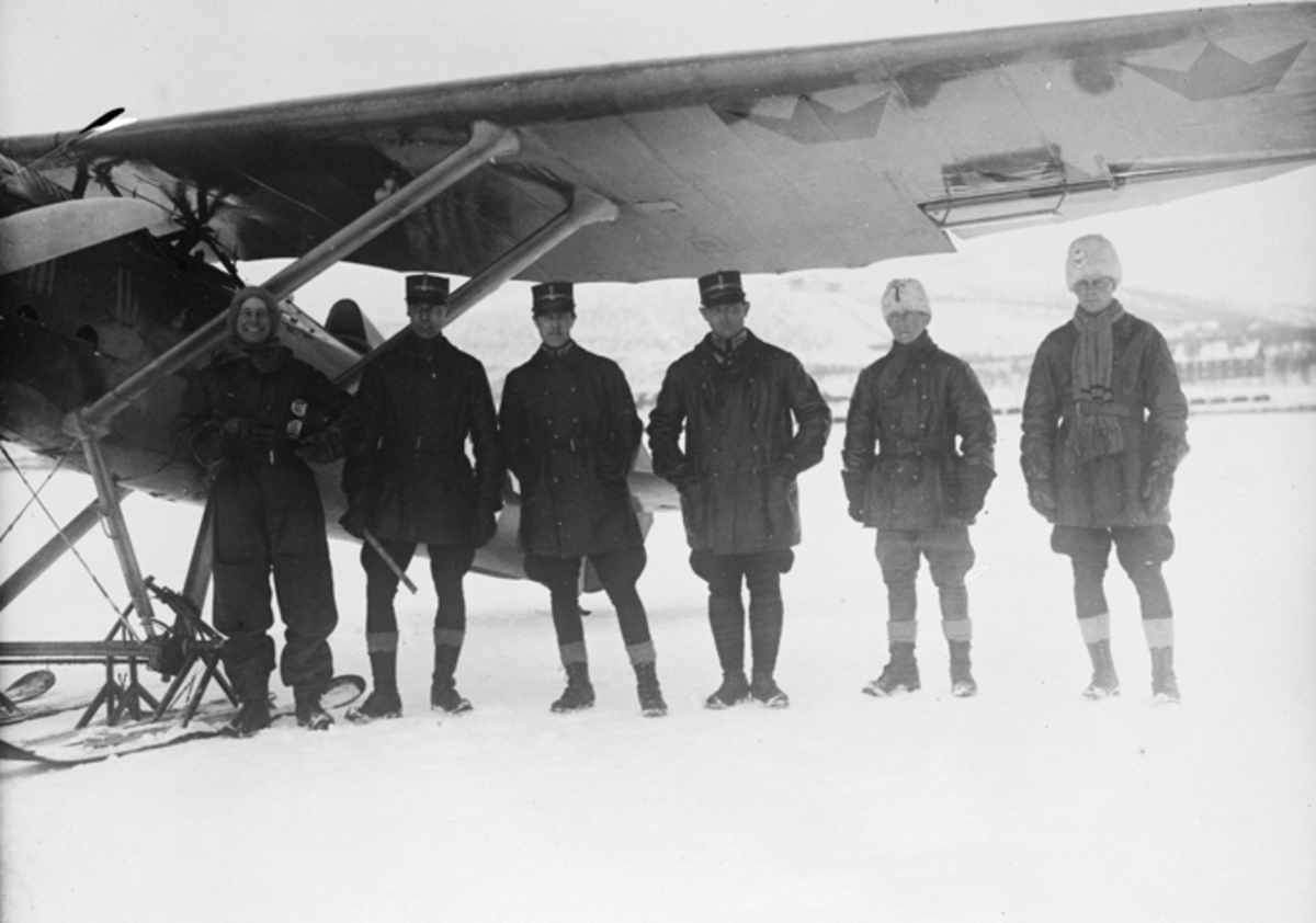 Grupporträtt vid provflygavdelningen i Kiruna. Sex män vid flygplan FVM J 23 på skidor.