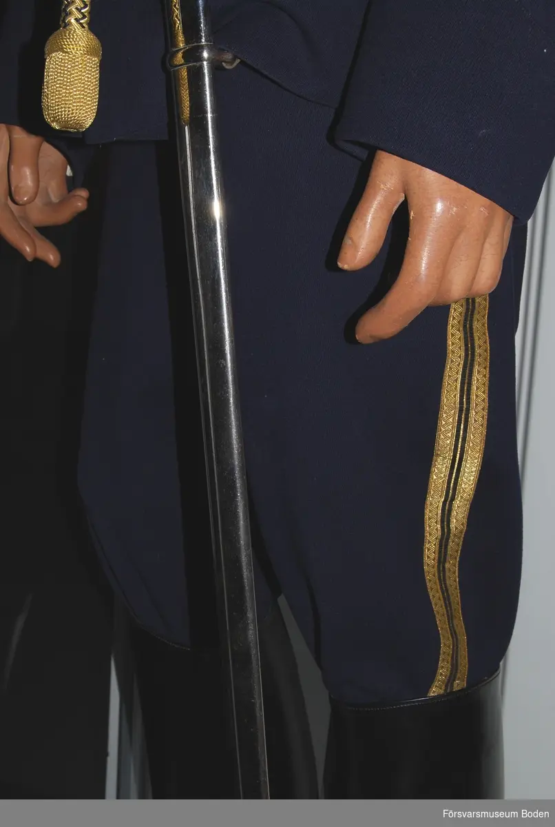 Mörkblått kläde med dubbla guldgaloner längs yttersömmarna och mellan dem en smal rand i guld. Guldgalon betecknar officerare.