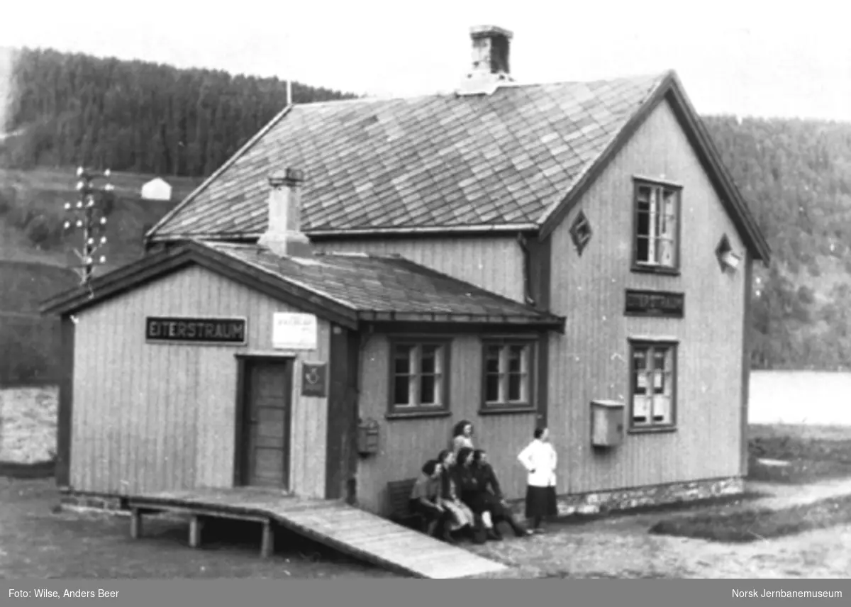 Eiterstraum stasjonsbygning; seks personer på benken og stående utenfor bygningen