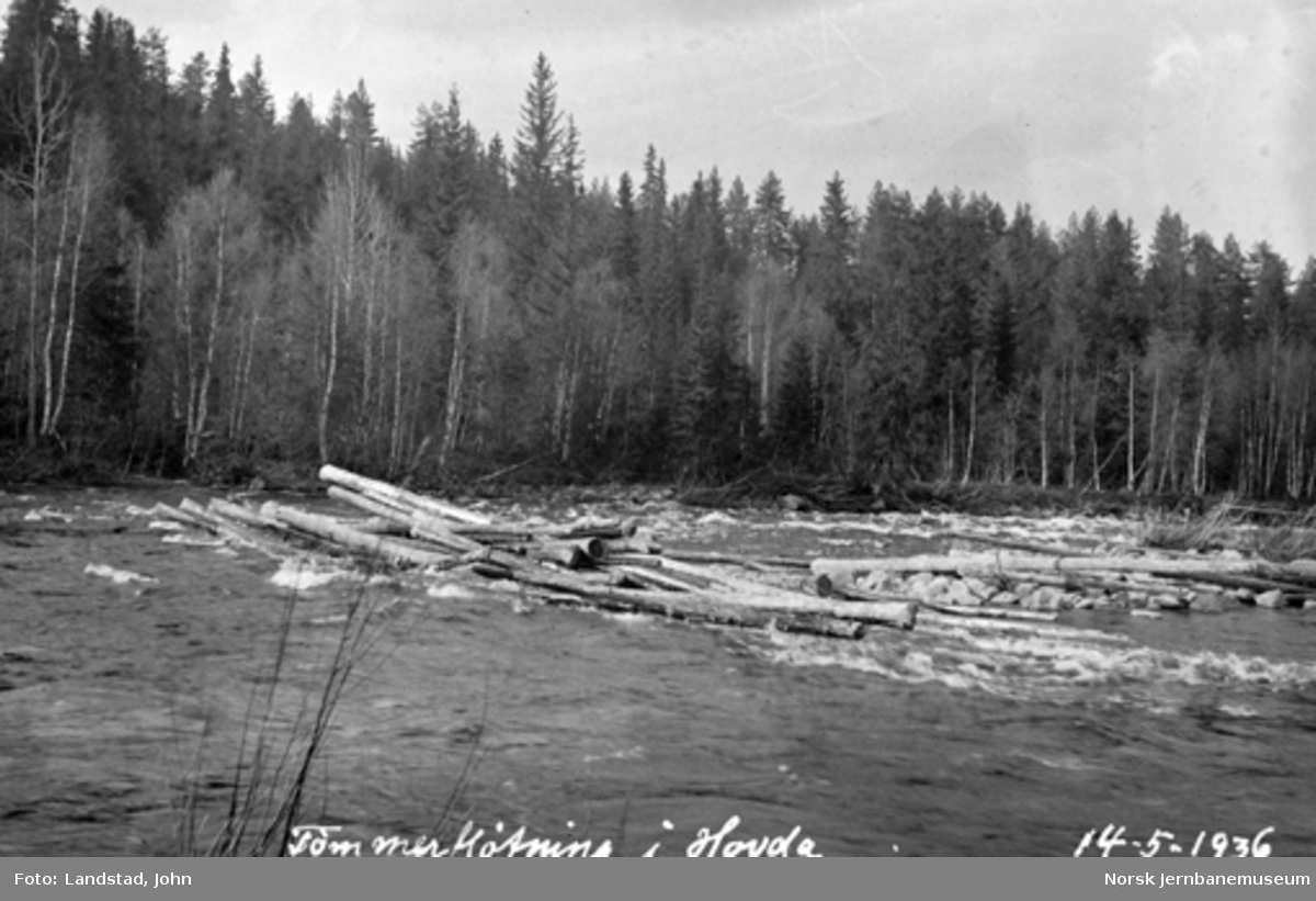 Tømmerfløting i Hovda elv med oppdemmet tømmer på holmen nedenfor vegbrua før hovedmassen ble sluppet