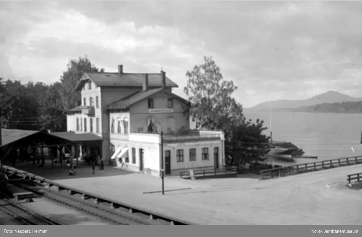 Eidsvoll stasjon, fotografert fra vegbrua. En nedrigget D/S Dronningen som lekter ved kaia.