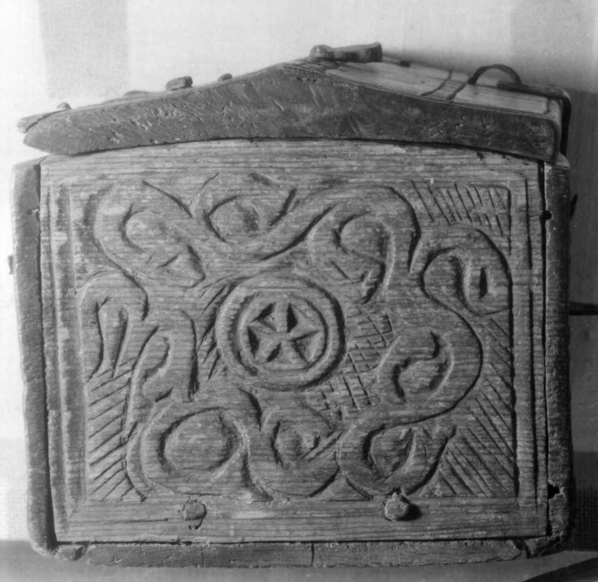 Skrin med flate sider of lett takformet lokk. Hengslet i bakkant og låsmekanisme i forkant. Håndtak midt på lokket. Hele utsidenhar skurd dekor med ranker, dyr og mennesker.