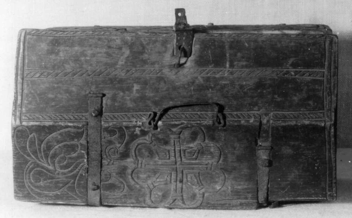 Skrin med flate sider of lett takformet lokk. Hengslet i bakkant og låsmekanisme i forkant. Håndtak midt på lokket. Hele utsidenhar skurd dekor med ranker, dyr og mennesker.