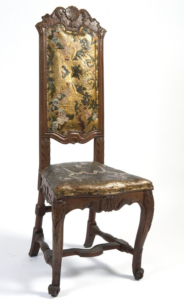 Regence-stol med ornamentikk i tre- og gyldenlærsarbeide som knytter den til rokokko-perioden.