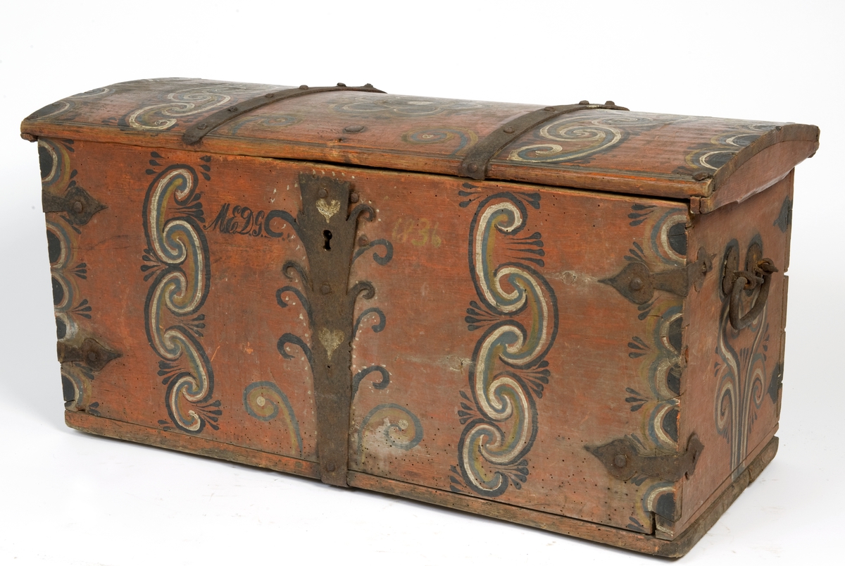 Kiste med svakt buet lokk. Malt dekor på alle sider og jernbeslag.