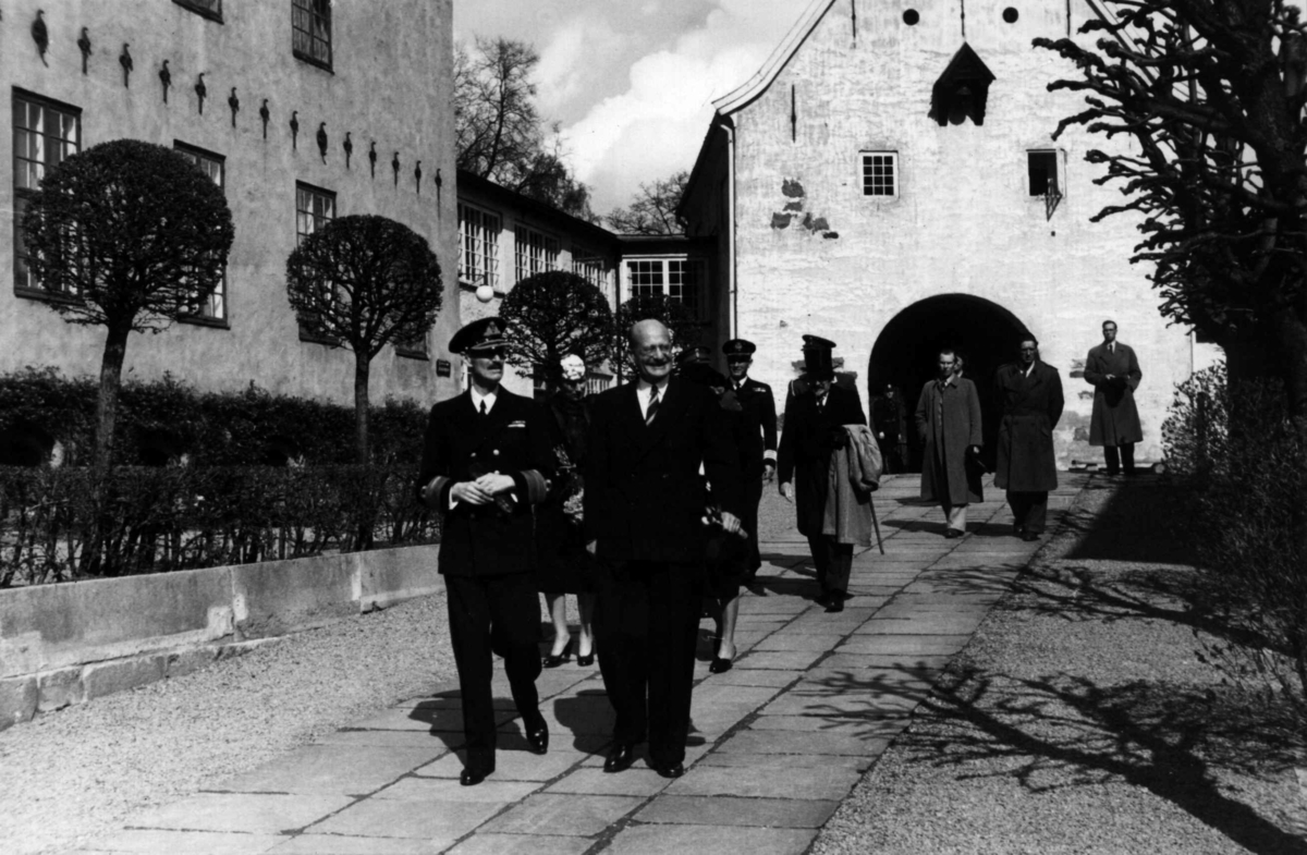 Gjenåpningen av samlingene, den 3. mai 1946. De kongelige, med Kong Haakon VII i spissen, ankommer museet og blir tatt imot av direktør Hans Aall og godseier Fearnly.