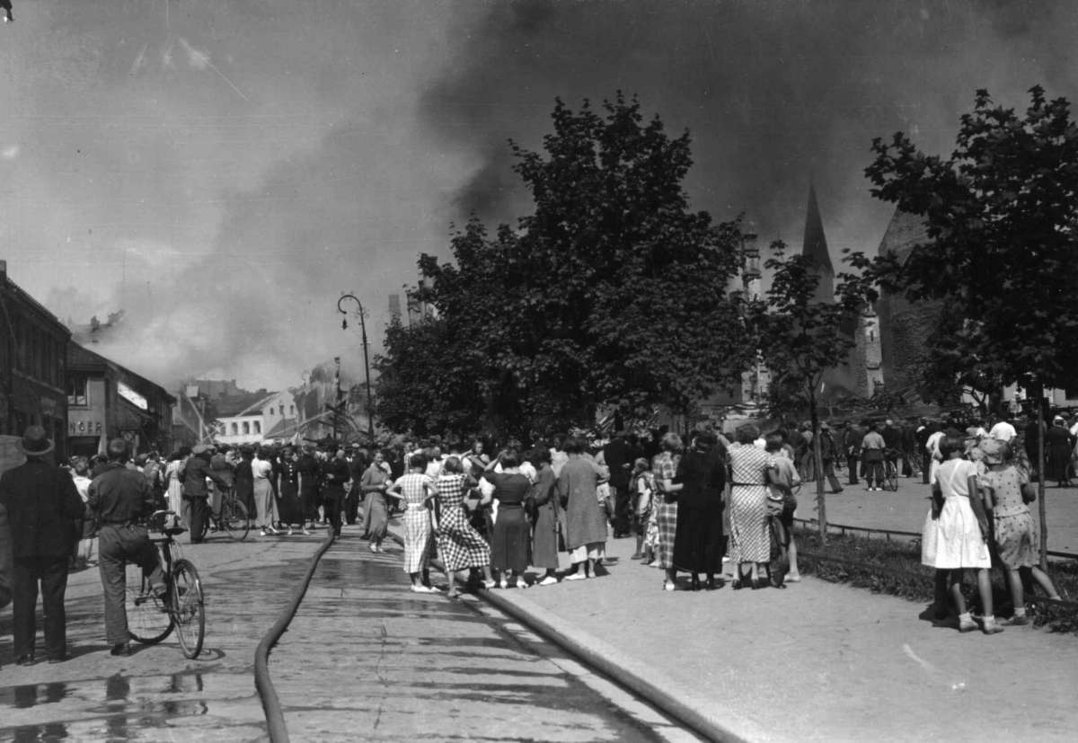Hamar, Hedmark. 1935. Brann i byen. Røyk. Bygate. Tilskuere. Brannslanger. Kirke i bakgrunnen.