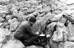 Kvinne lager mat i steinur på Hardangervidda.
