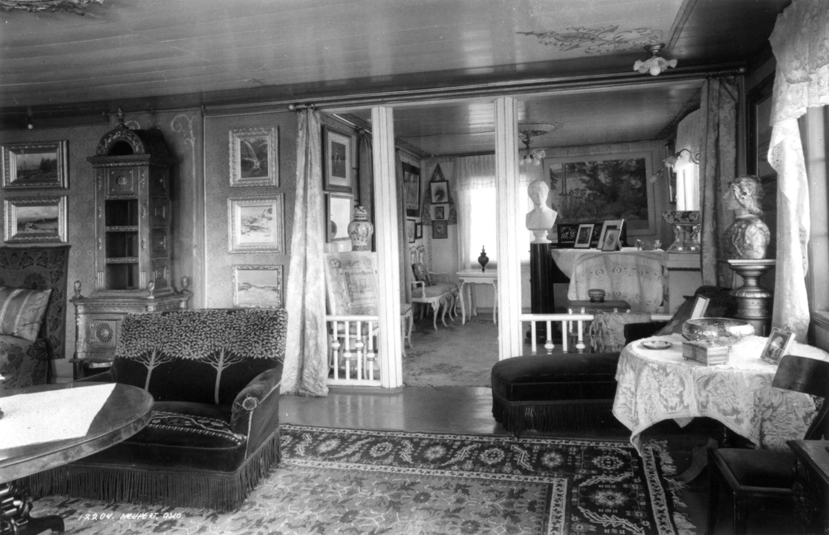 Aulestad, Gausdal 1935. Karoline og Bjørnstjerne Bjørnsons hjem. Interiør stuer.  Begge stuer møblert med sofaer, stoler og bord.  Tepper på gulvene. Malerier og fotografier på veggene. Skulpturer og pyntegjenstander på bordene.