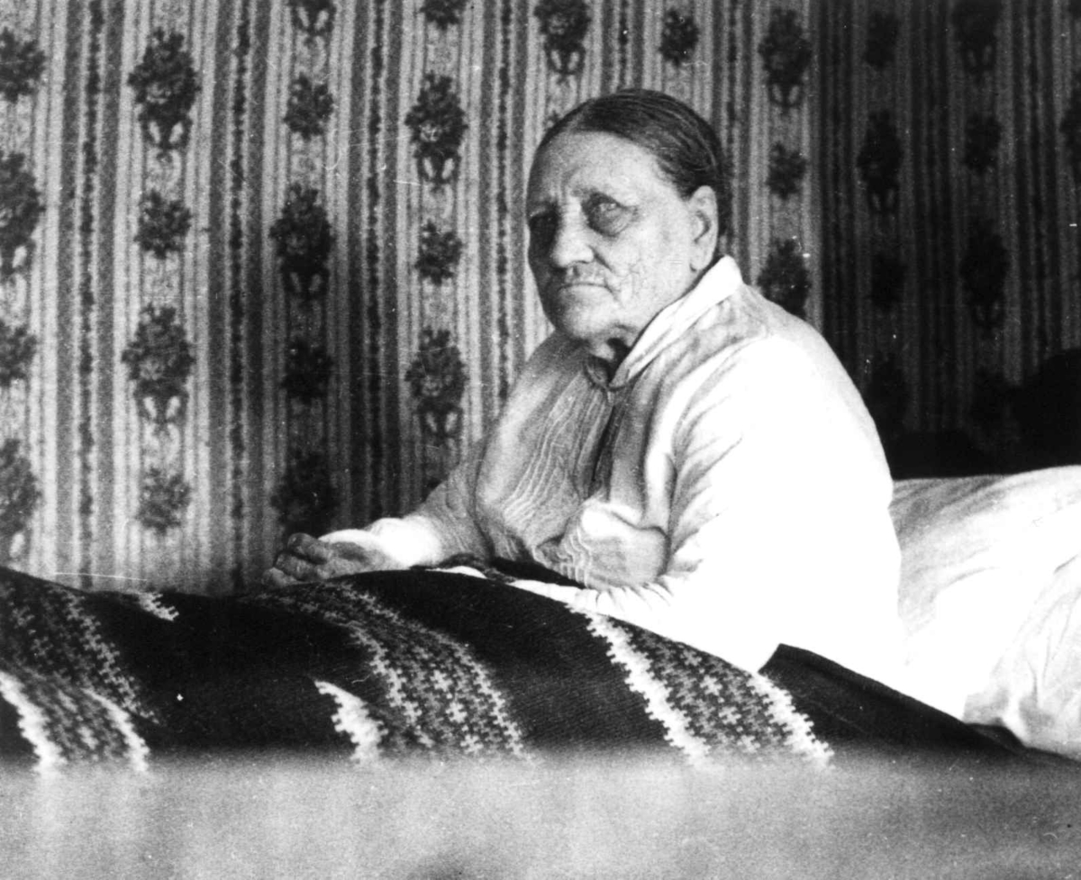 Fru Åselina Eiken sitter i sengen sin. Eiken, Hægesbostad, Vest-Agder 1937.