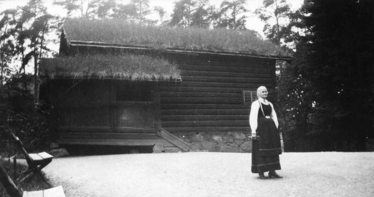 Ansatte, forøvrig museets eldste person i 1929,  Asgjerd Haugen utenfor Hovestua, bygning nr.182, på Norsk Folkemuseum.