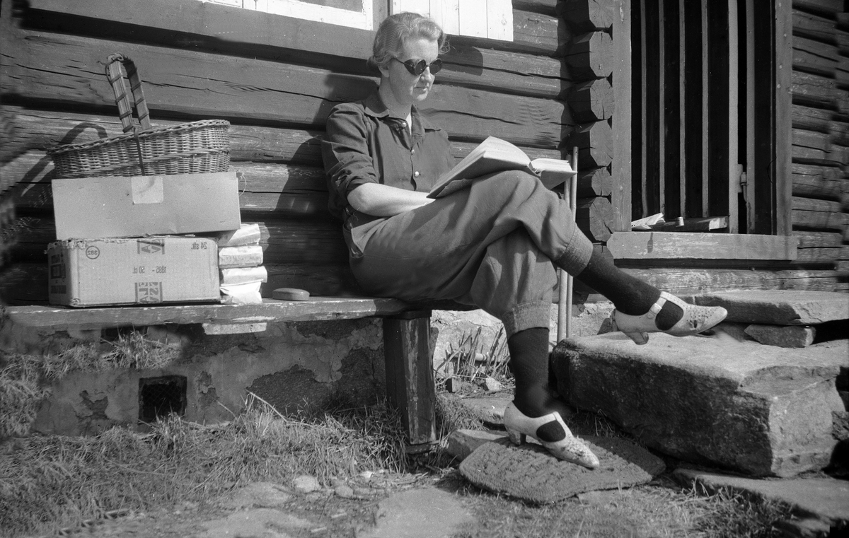 Dordi Arentz sitter utenfor en hytta og leser.  Fotografert påsken 1946.