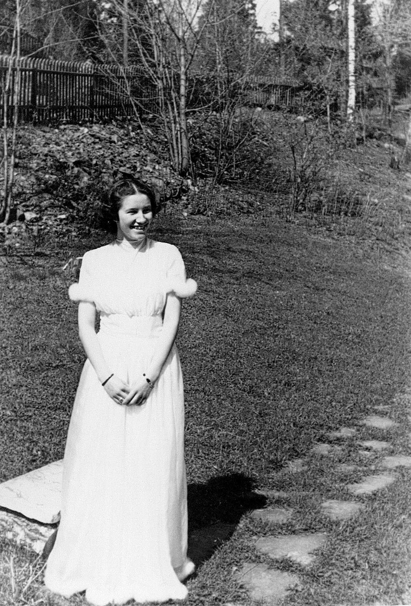 Inger Fougli i hagen på Jar, Bærum, Akershus, på konfirmasjonsdagen sin 6.mai 1945. Dette var dagen før freden brøt løs, altså siste dag under krigen. 