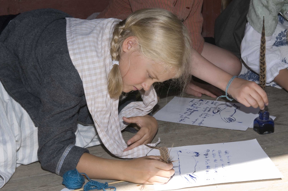 Levendegjøring på museum.
Elevene tegner og skriver med fjærpenn, Ferieskolen uke 30 i 2008.