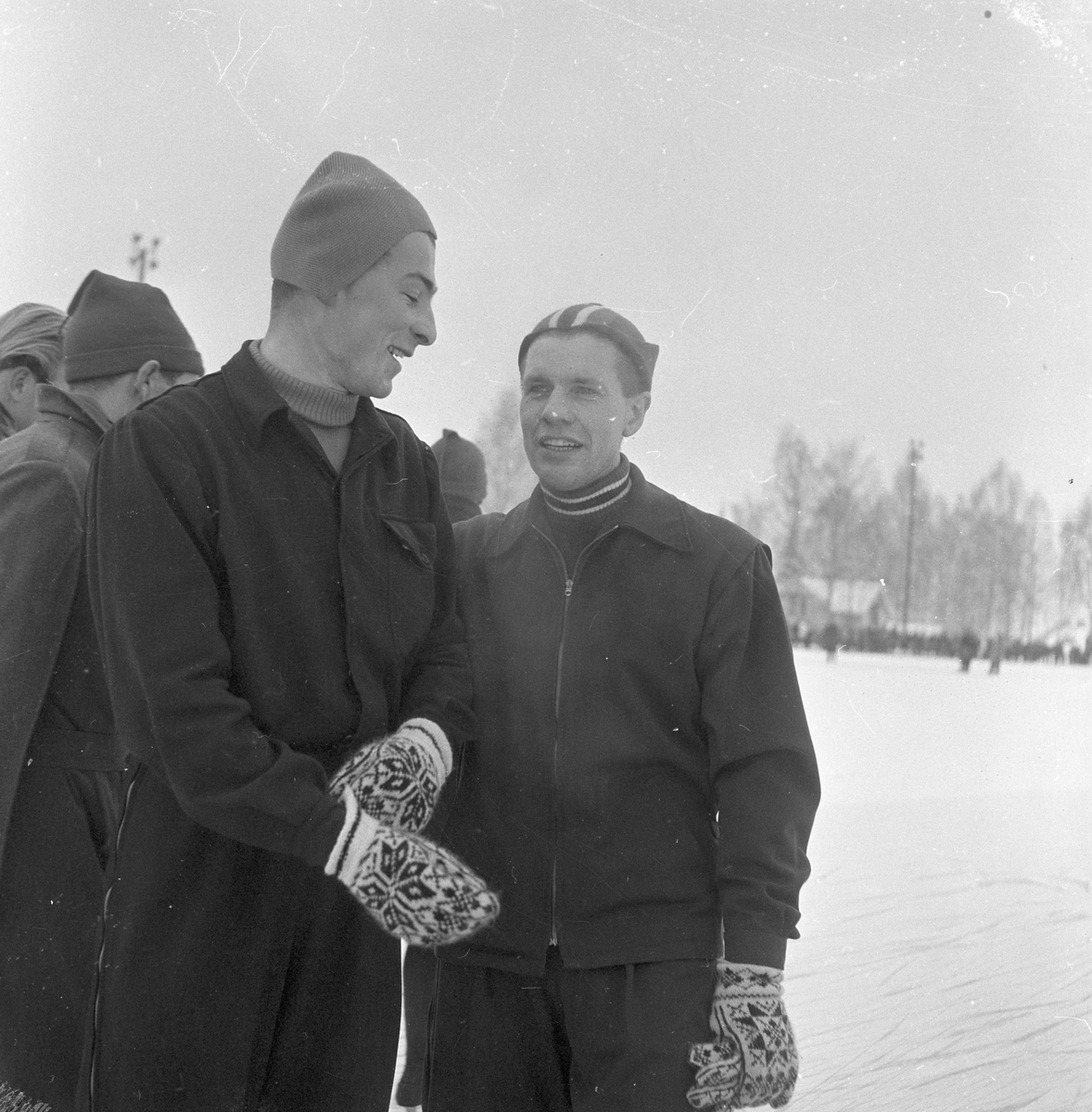 Skøyteløperen Sverre Haugli og Finn Helgesen står på skøytebane og prater.