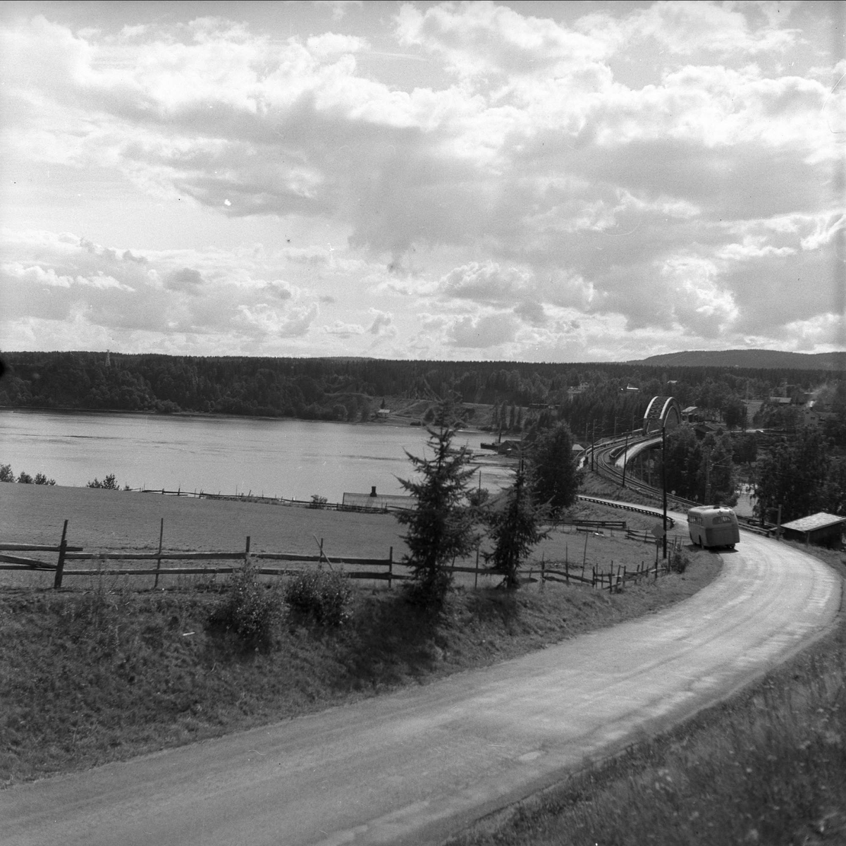 Minnesund, Akershus, 10.08.1956. Landskap med vei og den gamle jernbanebrua med påhengte kjørebaner for bil.