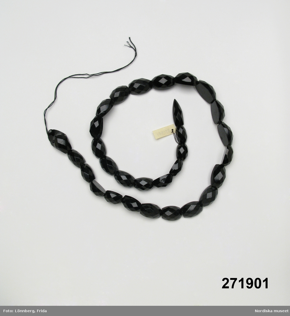 Huvudliggaren:
"Halsband?, svart konstmassa; kedja i form av orm; 30 st facetterade numrerade delar uppträdda på svart snodd. L 58 cm. Tillh. giv. mormor."