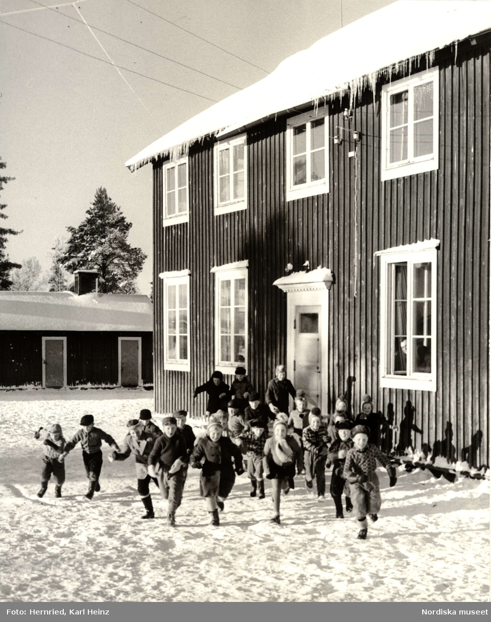 Skola i Korpilombolo, Norrbotten. Exteriör med skolbyggnad och skolbarn ute i snö
