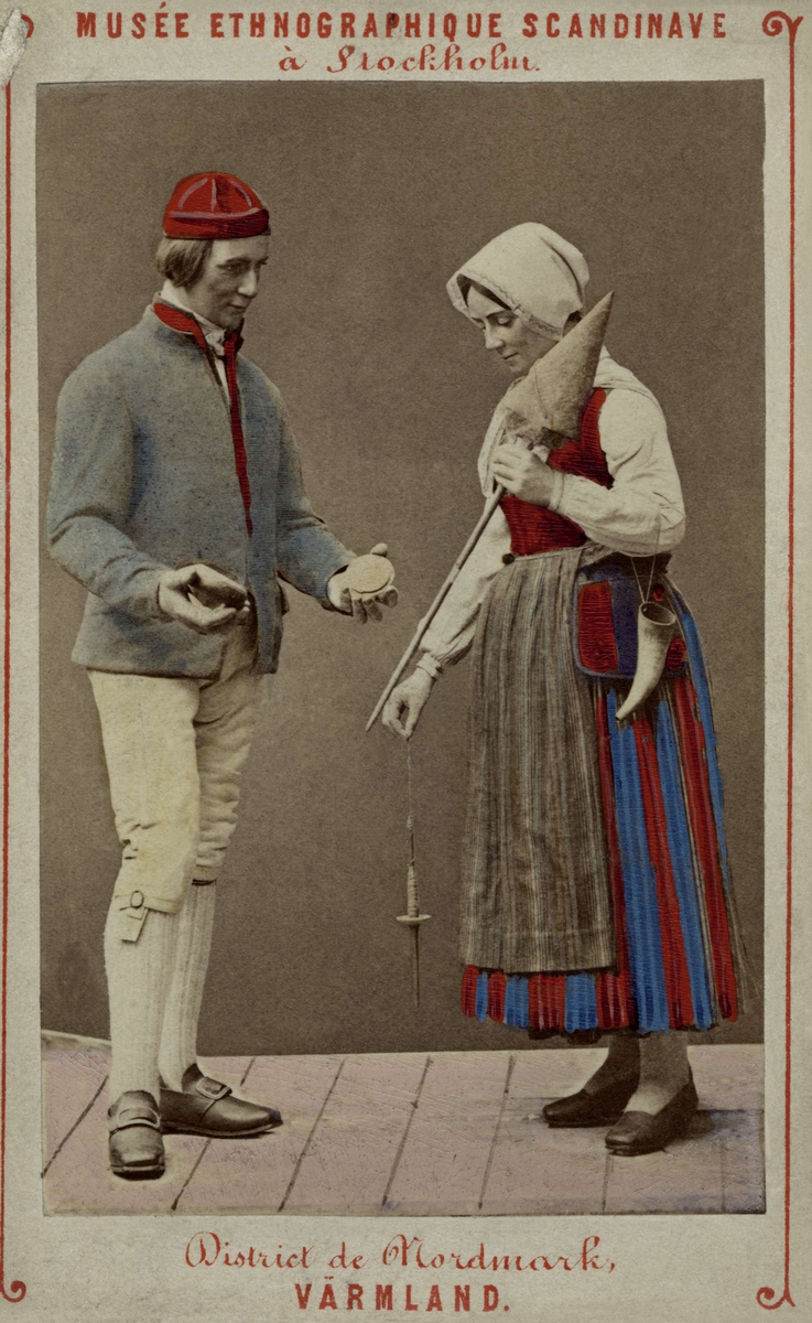 Handkolorerat fotografi av man och kvinna i sockendräkter från Nordmark, Värmland. Skandinavisk-etnografiska samlingen, Stockholm.