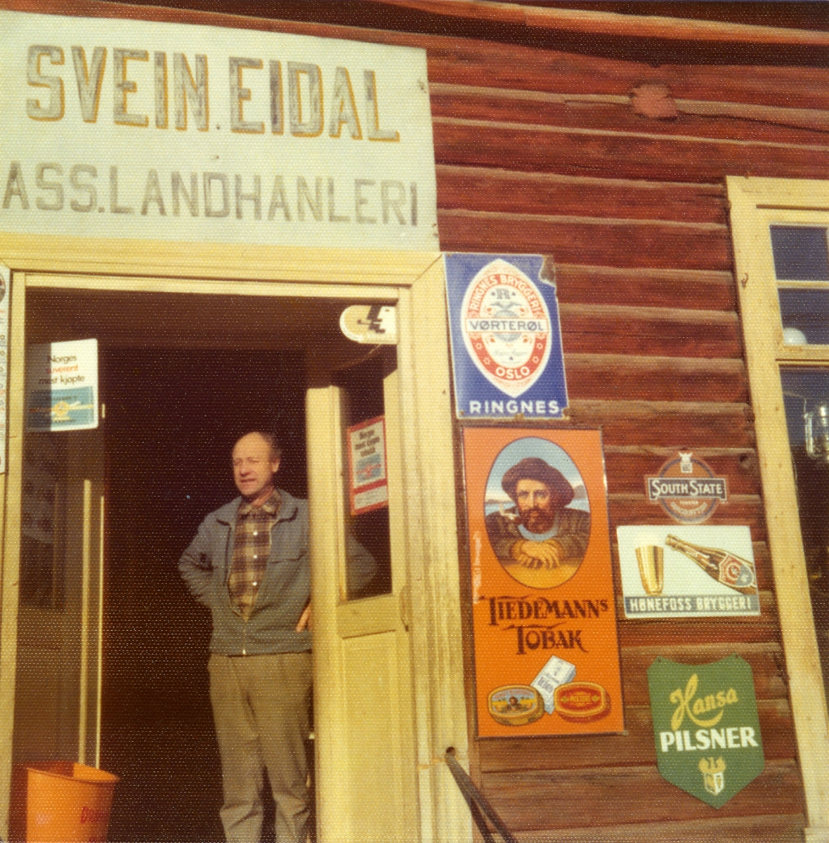 Gamle reklameskilt på fasaden til landhandel Svein Eidal.