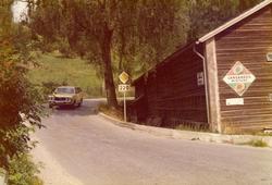 En bil kjører forbi et hus med reklameskilt på fasaden.