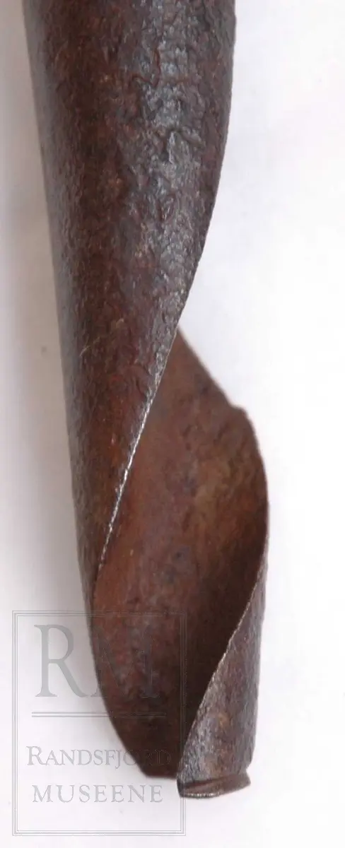 Bor av smidd jern, med tverrstilt håndtak av tre i motsatte ende.