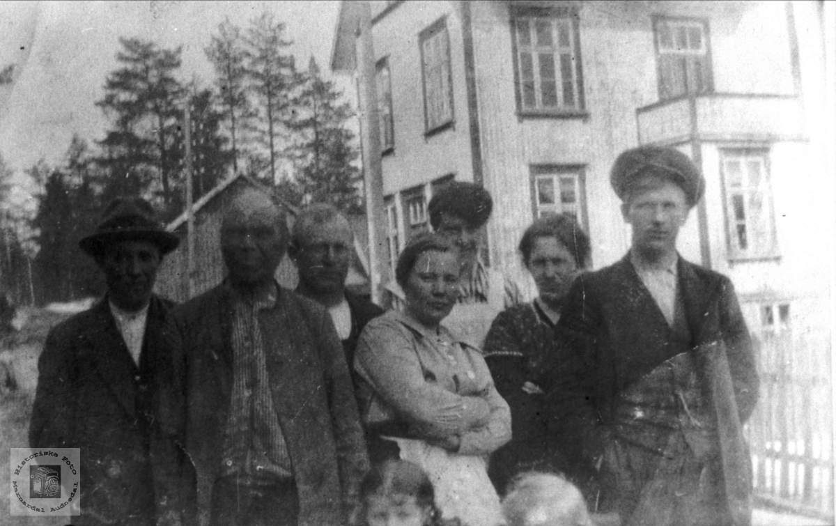 Gruppeportrett med heradshuset på Bjelland i bakgrunnen.