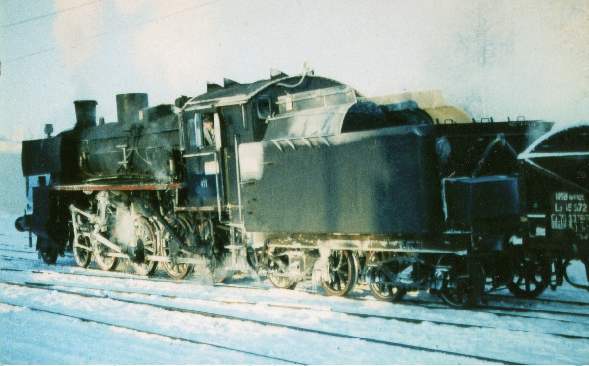 Damplokomotiv type 26c nr. 411 har ankommet Kongsvinger stasjon med godstog fra Elverum en kald vinterdag.