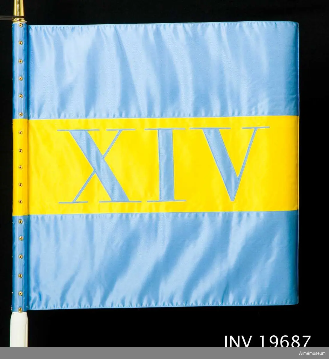 Maskinsytt och dubbelsidigt. Det har tre stycken 220 mm breda våder i blått, gult, blått. I mitten av det gula fältet finns de romerska siffrorna XIV.