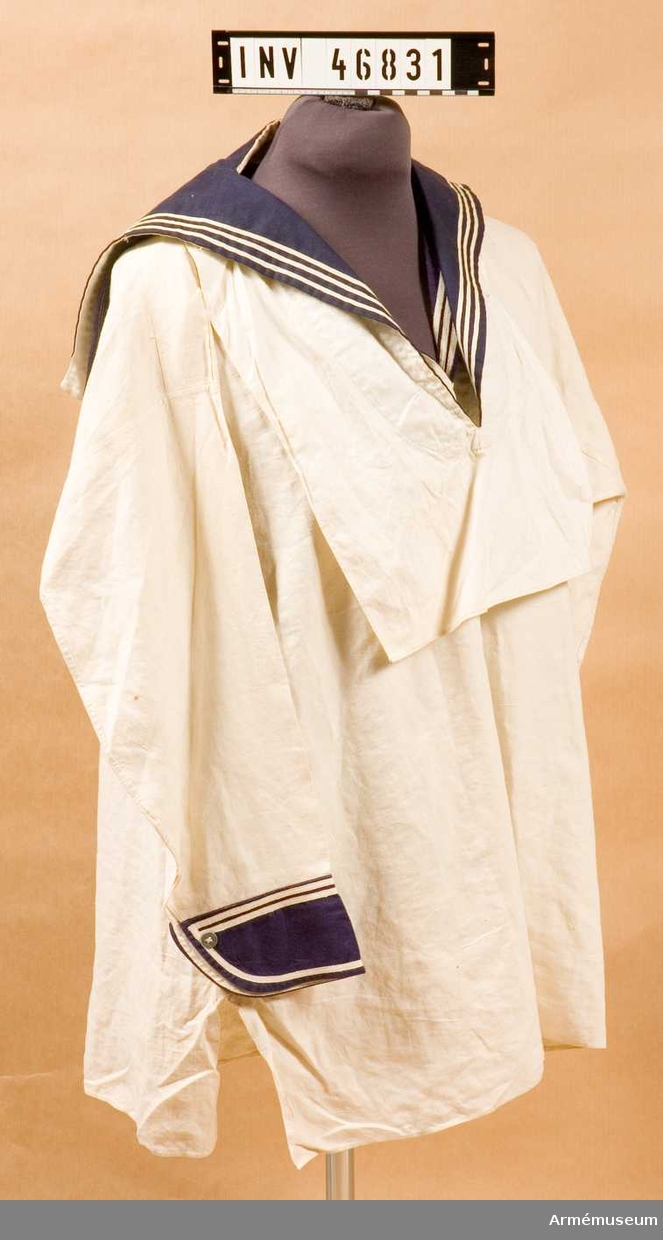 Grupp C I.
Skjortan är blåkragad, har lång ärm av vitt linnetyg med påstickade manschetter av samma tyg som kragen. 